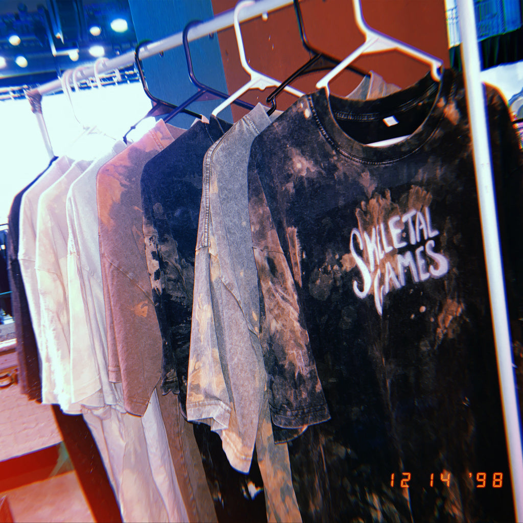 T-shirts on a rack with 'Skeletal Games' logo in a store setting.